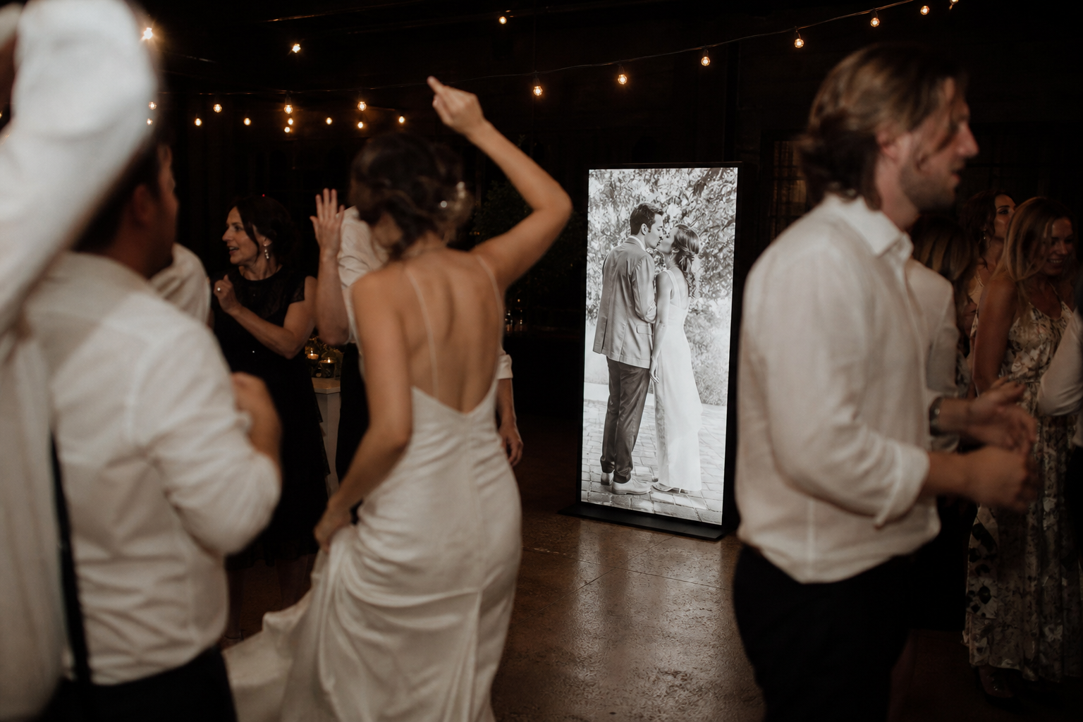 Guests dancing beside a glowing black-and-white photo of the couple's first kiss